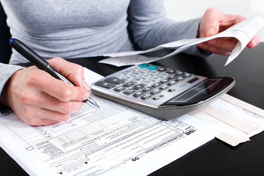 Woman looking at receipts with calculator and 1040 tax forms on desk