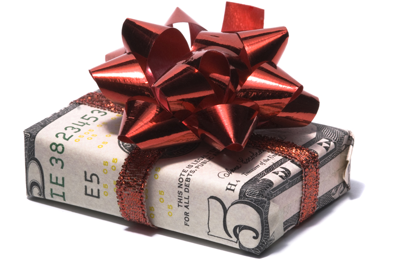Gift box wrapped in a five dollar bill with a red ribbon and bow on top