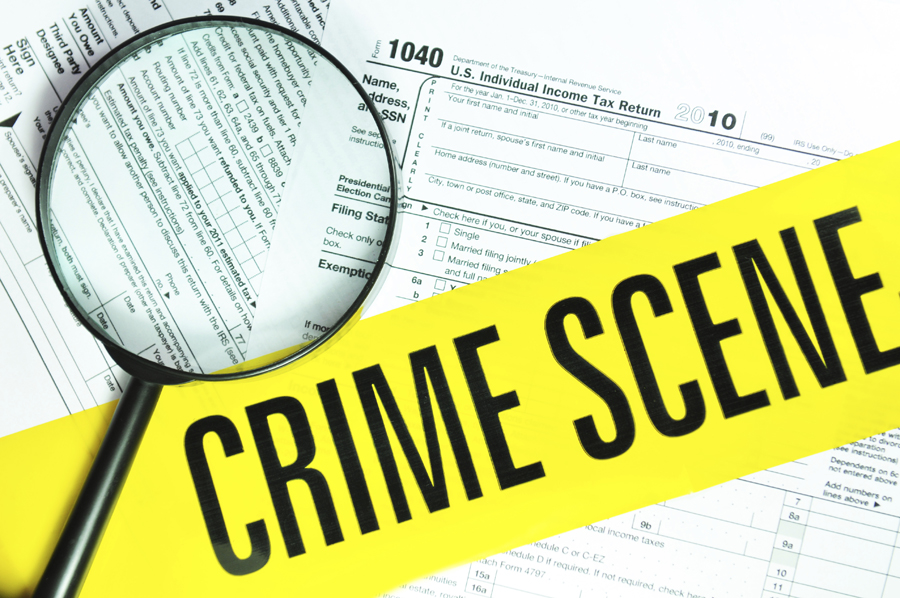 Crime scene tape and magnifying glass over 1040 tax forms