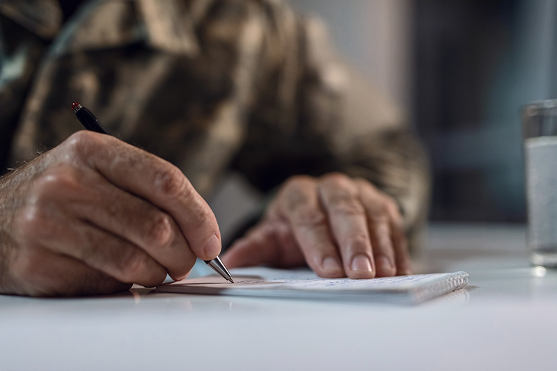 Armed Forces member writing on a notepad
