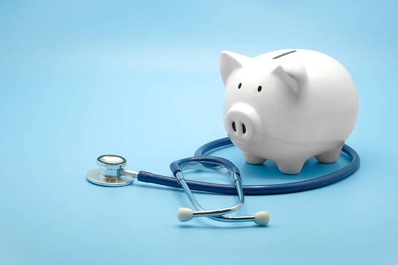 Piggy bank and stethoscope on blue background