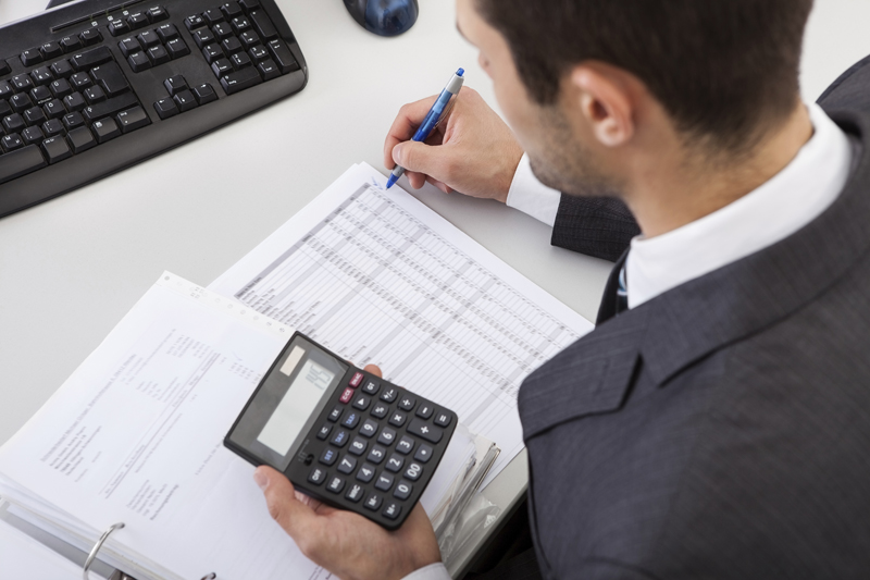 Man working at desk holding a calculator
