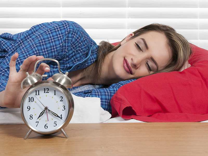 woman hitting the snooze button on alarm