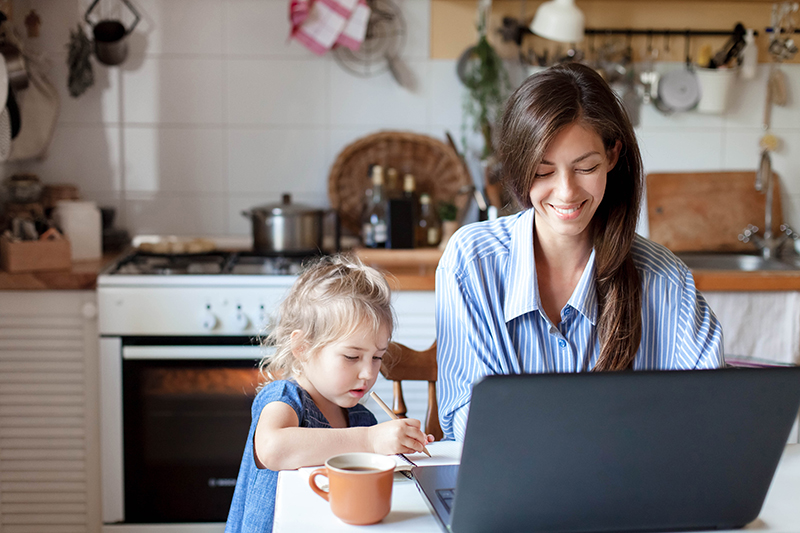 Woman working from home with child next to her
