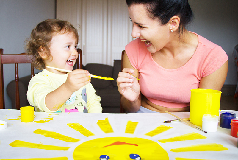 babysitter painting a sun with a child