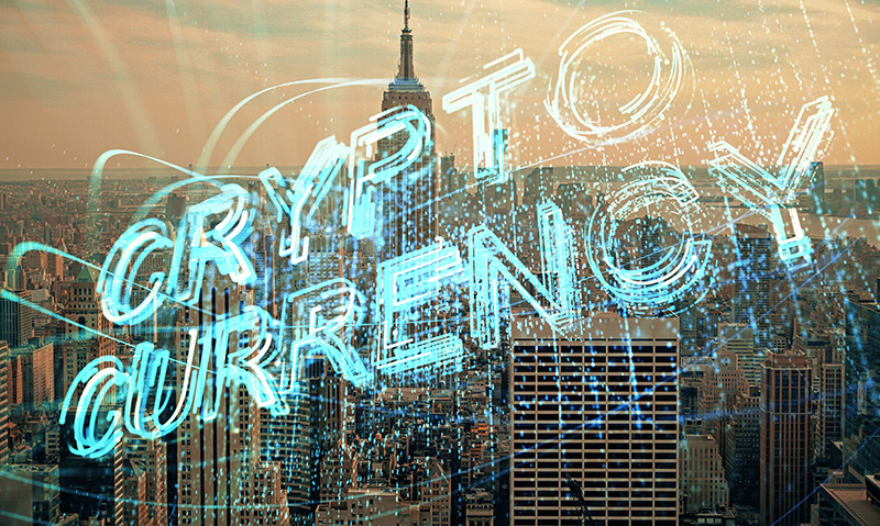 Crypto Currency written in lights with a city in the background