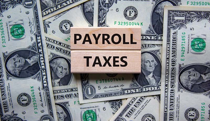 Payroll Taxes Sign on top of dollar bills