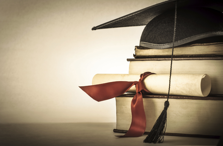 stacked books, diploma, and graduation hat