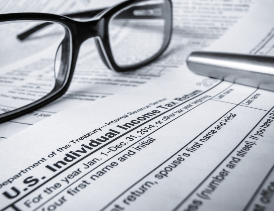 glasses and pen laying on top of tax form