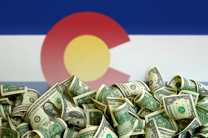 State of Colorado flag with a pile of money in front of it