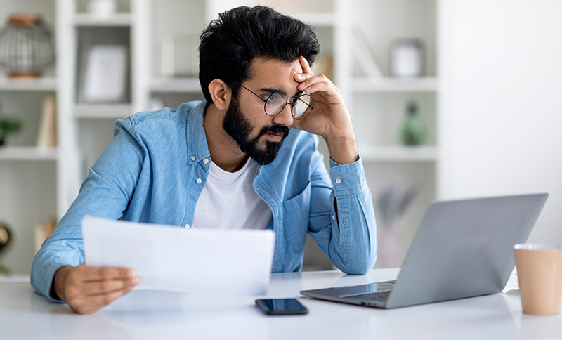 Man reading a letter and laptop computer