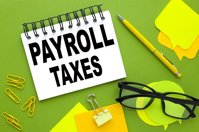 Payroll Taxes written on notepad with green background