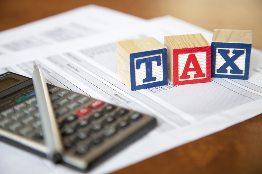 Pen, calculator, and blocks that spell out TAX on financial papers