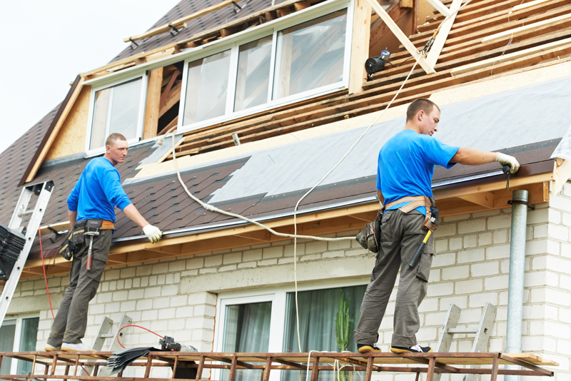 Two men fixing a roof