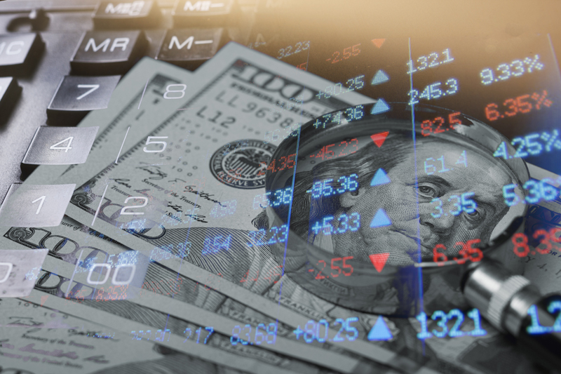 $100 bills with magnifying glass and stock price chart