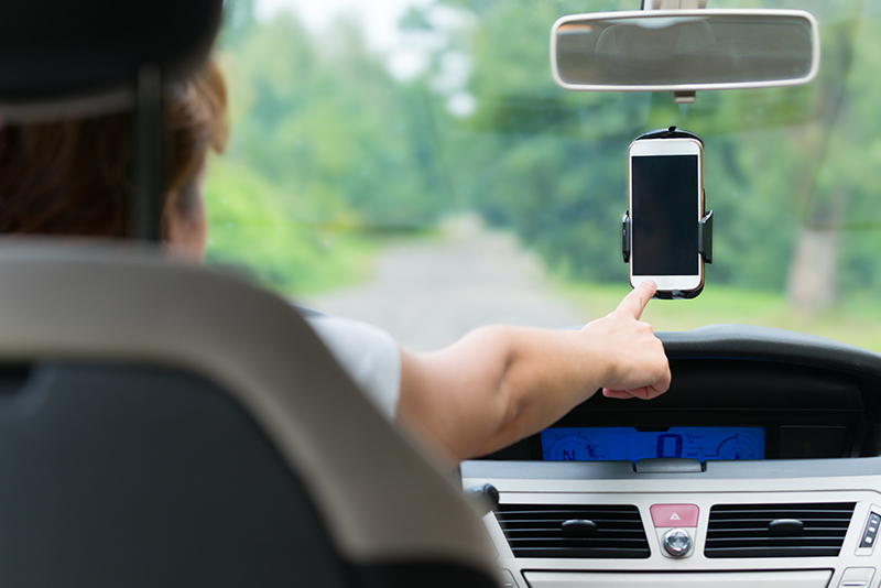 Driver pointing to a smart-phone attached to the windshield