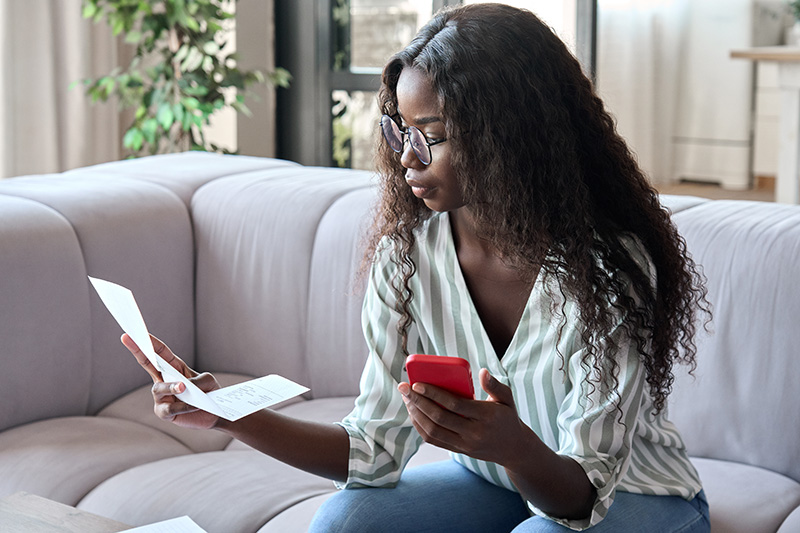 Woman reading a letter and holding her phone