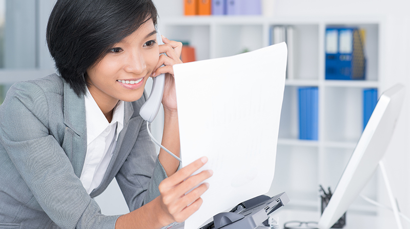 woman on the phone while holding paperwork