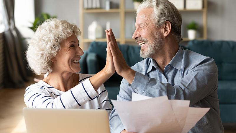 Mature couple high fives while looking over paperwork