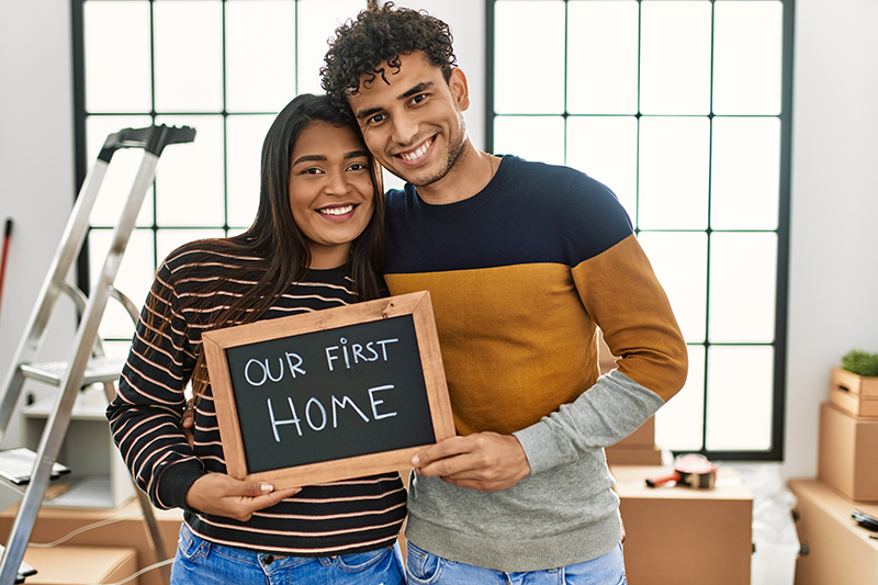 Couple holding a sign that says Our First Home
