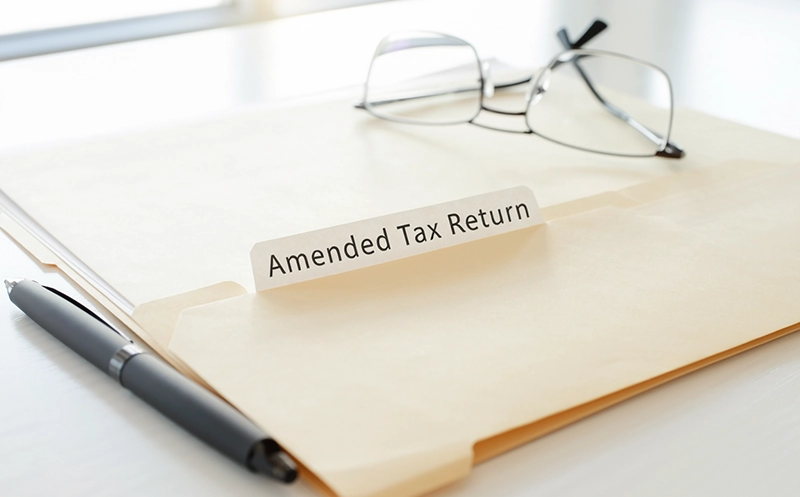 Manila folder with Amended Tax Return label along with glasses and a pen