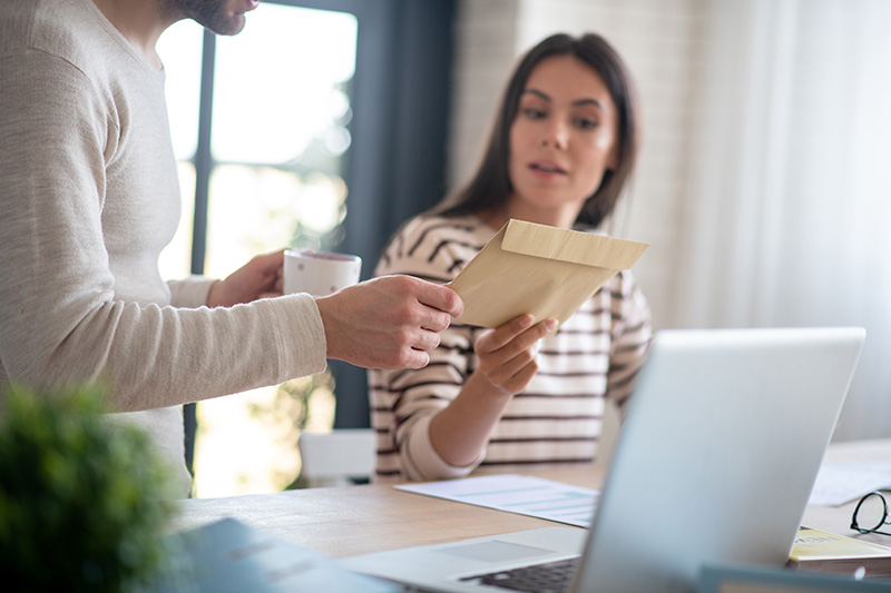 Man handing a woman a letter