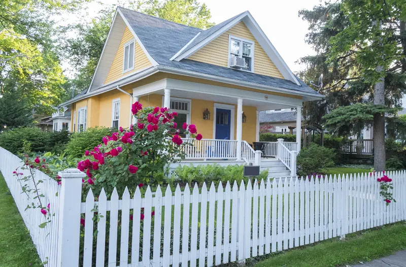 Yellow house with white fence