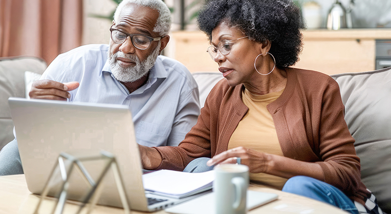 Retired Couple looking at paperwork and a computer